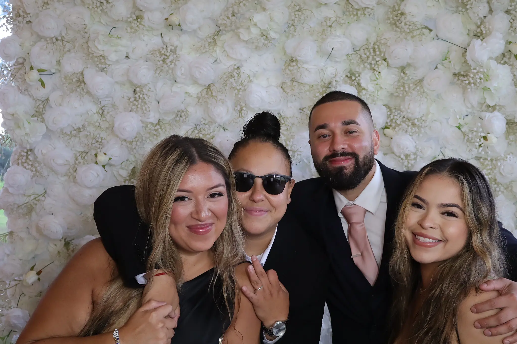 Wedding guests celebrating together in front of the floral wall by Images & Creations