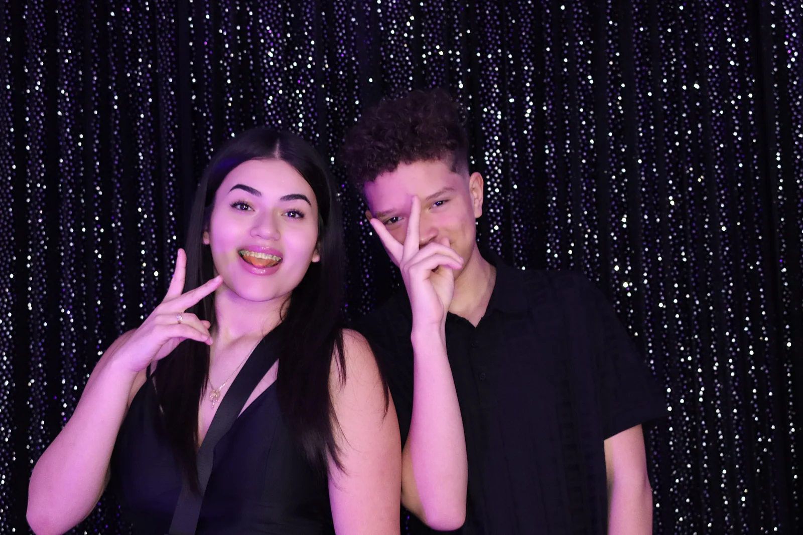 Two young guests posing against a black shimmer backdrop by Images & Creations